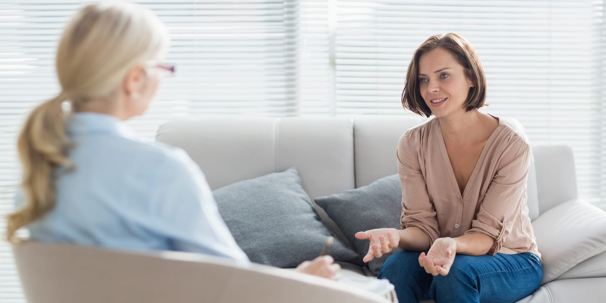 Eine Frau auf einer Couch spricht zu einer gegenüber sitzenden Frau