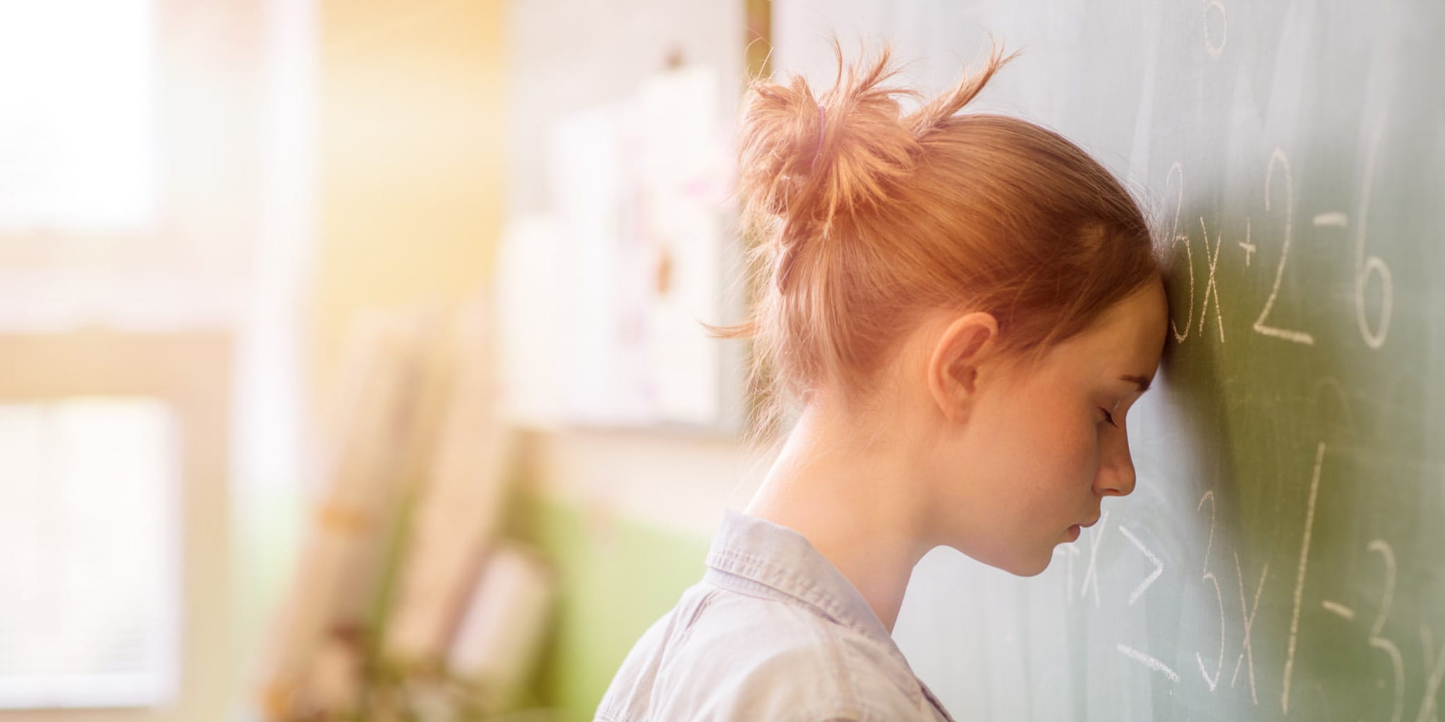 Ein Mädchen lehnt mit dem Kopf an einer Tafel