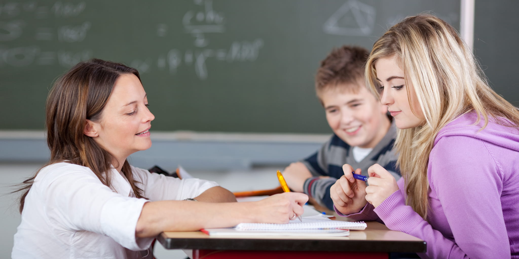 Lehrerin bespricht eine Aufgabe mit einer Schülerin an ihrem Tisch