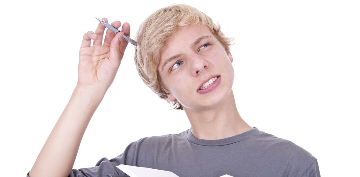 Ein Junge kratzt sich mit dem Stift am Kopf und schaut nachdenklich nach oben